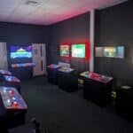Indoor arcade with pinball machines and video game screens at Arcade Time Machine.