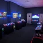 Indoor arcade with multiple gaming machines and neon lighting at Arcade Time Machine.